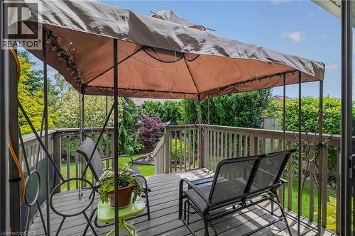 Multi-level wood deck featuring a protective canopy, decorative metal railing, and steps descending to a landscaped yard - 51 Millcroft Drive, Simcoe, ON - Outdoor With Deck Patio Veranda With Exterior