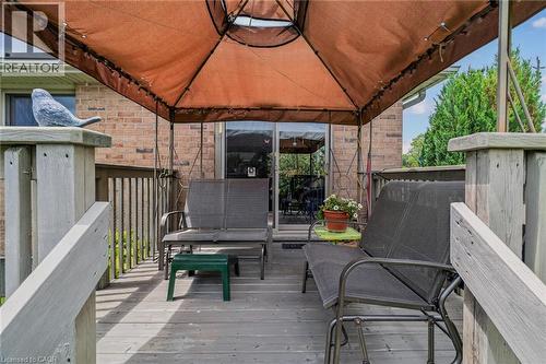 Expansive wood-finish deck featuring a brown gazebo canopy, brick exterior, and glass sliding doors - 51 Millcroft Drive, Simcoe, ON - Outdoor With Deck Patio Veranda With Exterior