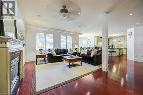 Spacious living area featuring rich wood-finish flooring, a decorative fireplace with a substantial mantel, and white plantation shutters on multiple windows - 4278 Clubview Drive, Burlington, ON - Indoor Photo Showing Living Room With Fireplace