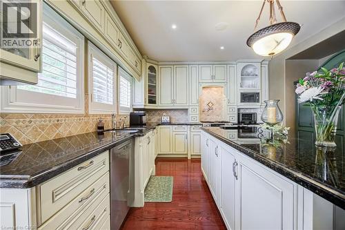 Kitchen featuring white cabinetry, dark stone countertops, and a full-height tile backsplash - 4278 Clubview Drive, Burlington, ON - Indoor Photo Showing Kitchen With Upgraded Kitchen