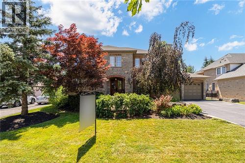 Stone facade residence featuring an arched front entrance and mature landscaping - 4278 Clubview Drive, Burlington, ON - Outdoor