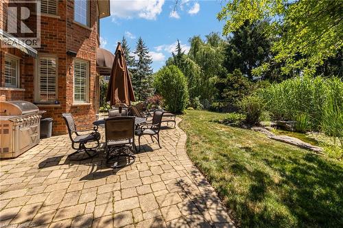 Brick exterior featuring multiple windows with louvered shutters and a curved stone paver patio - 4278 Clubview Drive, Burlington, ON - Outdoor With Deck Patio Veranda