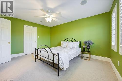 Bedroom featuring green walls, light-toned carpeting, a ceiling fan with integrated lighting, two white panel doors, and window shutters - 4278 Clubview Drive, Burlington, ON - Indoor Photo Showing Bedroom