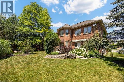 Expansive green lawn surrounds a brick exterior featuring multiple windows and a rounded bay extension - 4278 Clubview Drive, Burlington, ON - Outdoor