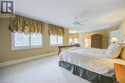 Bedroom featuring light beige carpeting, two large windows with plantation shutters and decorative valances, and a ceiling fan - 4278 Clubview Drive, Burlington, ON - Indoor Photo Showing Bedroom