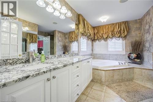 Spacious bathroom featuring a dual vanity with a granite countertop, white cabinetry, and brushed nickel hardware - 4278 Clubview Drive, Burlington, ON - Indoor Photo Showing Bathroom