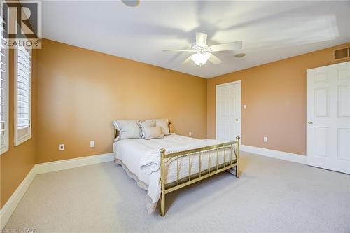 Carpeted room featuring a ceiling fan with integrated lighting, two paneled doors, and two windows with plantation shutters - 4278 Clubview Drive, Burlington, ON - Indoor Photo Showing Bedroom