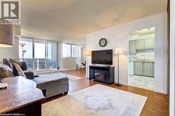 Open-concept living area featuring wood-finish flooring, a wall of windows, and a sliding glass door leading to a private balcony - 