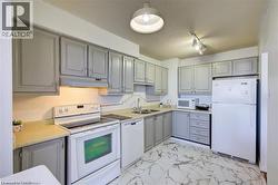 Kitchen featuring light gray cabinetry, white appliances, and a double basin sink - 