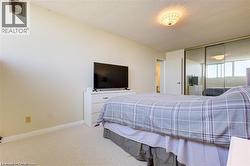 Wall-to-wall carpeted bedroom featuring a textured ceiling, a built-in ventilation grate, and sliding mirrored closet doors - 