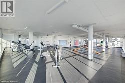 Spacious fitness center featuring expansive windows, rubber flooring, exposed ceiling ducts, and multiple exercise machines - 