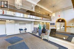 Spacious lobby with patterned carpet flooring, dual chandeliers, and an arched entry - 