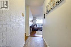 Hallway featuring textured white brick-patterned wall and wood-finish flooring - 