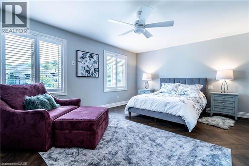Spacious bedroom featuring wood-finish flooring, light grey walls, and two large windows with horizontal blinds - 76 Adriatic Boulevard, Hamilton, ON - Indoor Photo Showing Bedroom