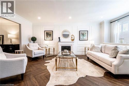 Herringbone wood-finish flooring complements a formal living space featuring a fireplace with a classic mantel - 76 Adriatic Boulevard, Hamilton, ON - Indoor Photo Showing Living Room With Fireplace