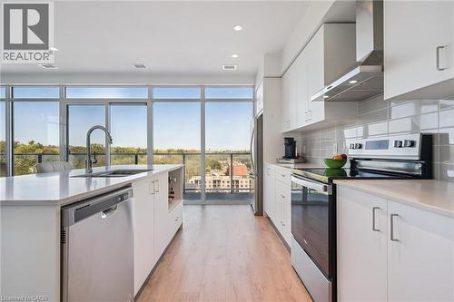 Modern kitchen featuring light wood-finish flooring, white cabinetry, and stainless steel appliances - 15 Glebe Street Unit# 902, Cambridge, ON - Indoor Photo Showing Kitchen