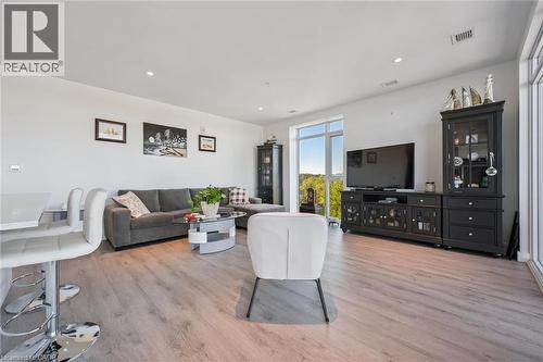 Open-concept living space featuring wood-finish flooring, recessed lighting, and a large window offering expansive outdoor views - 15 Glebe Street Unit# 902, Cambridge, ON - Indoor Photo Showing Living Room
