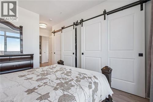White paneled barn doors with black hardware - 15 Glebe Street Unit# 902, Cambridge, ON - Indoor Photo Showing Bedroom