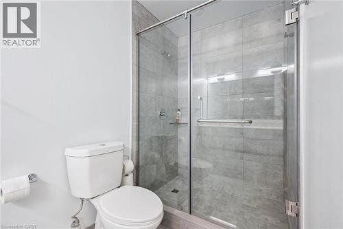 Walk-in shower featuring a glass enclosure with a chrome pull handle and light gray large format tile walls and flooring - 15 Glebe Street Unit# 902, Cambridge, ON - Indoor Photo Showing Bathroom
