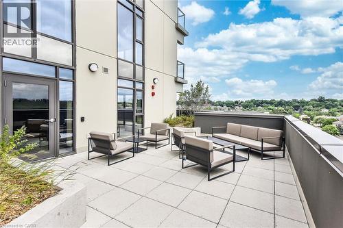 Spacious outdoor patio featuring light-toned square pavers, a contemporary metal railing, and a concrete planter box - 15 Glebe Street Unit# 902, Cambridge, ON - Outdoor With Exterior