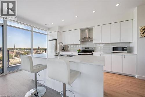 Modern kitchen featuring white cabinetry, stainless steel appliances, a center island with countertop seating, and wood-finish flooring - 15 Glebe Street Unit# 902, Cambridge, ON - Indoor Photo Showing Kitchen With Stainless Steel Kitchen With Upgraded Kitchen