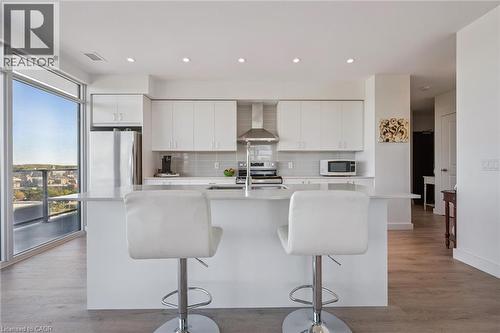 Modern kitchen featuring white cabinetry, light gray tile backsplash, stainless steel appliances, and a central island with an extended counter - 15 Glebe Street Unit# 902, Cambridge, ON - Indoor Photo Showing Kitchen With Stainless Steel Kitchen With Upgraded Kitchen