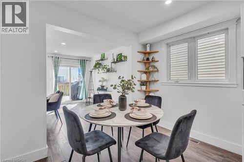 Bright dining area featuring a round table with a stone-finish top, wood-finish flooring, recessed lighting, and a window with horizontal blinds - 425 Erinbrook Drive, Kitchener, ON - Indoor Photo Showing Dining Room