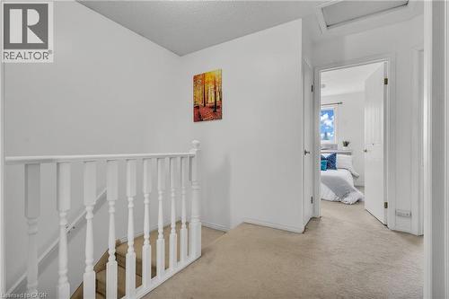 Upper-level hallway with neutral carpeting, white balustrade, and a doorway leading to a room featuring a window with natural light - 425 Erinbrook Drive, Kitchener, ON - Indoor Photo Showing Other Room