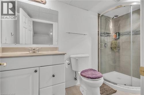 Full bathroom featuring a white vanity with integrated sink, light-toned countertop, and a glass-enclosed corner shower with tiled walls and a decorative accent band - 425 Erinbrook Drive, Kitchener, ON - Indoor Photo Showing Bathroom