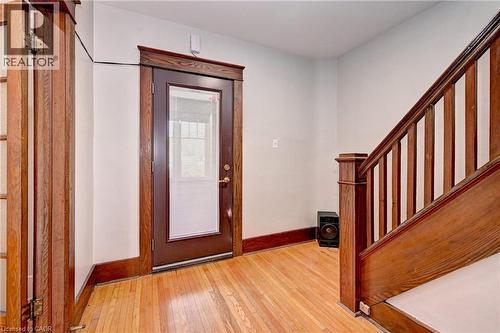 Entryway featuring wood-finish flooring, a dark wood-finish front door with an integrated window pane, rich wood-finish trim, and a wood-finish staircase with balusters - 147 Courtland Avenue E, Kitchener, ON - Indoor Photo Showing Other Room