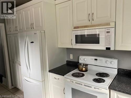 Kitchen featuring white cabinetry, dark speckled countertops, and an electric range with an over-the-range microwave - 1066 Richmond Street, London, ON - Indoor Photo Showing Kitchen