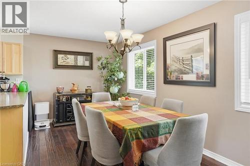 Dining area featuring wood-finish flooring, a multi-light chandelier, two windows with blinds, a built-in sideboard, and a breakfast bar with a stone countertop - 25 Saveryn Road, Hamilton, ON - Indoor Photo Showing Dining Room