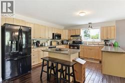 Kitchen featuring light wood-finish cabinetry, dark wood-finish flooring, and a central island with a granite countertop - 