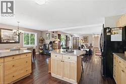 Kitchen featuring light wood cabinetry with granite countertops, a central island, and wood-finish flooring - 
