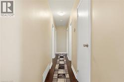 Hallway featuring light neutral wall paint, dark wood-finish flooring, and multiple white interior doors - 