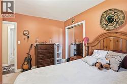 Bedroom featuring a light wood headboard, built-in mirrored closet doors, and wood-finish flooring - 