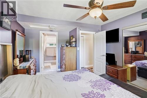 Bedroom with wood-finish ceiling fan, a mirrored closet door, and an open doorway leading to a tiled bathroom - 25 Saveryn Road, Hamilton, ON - Indoor Photo Showing Bedroom