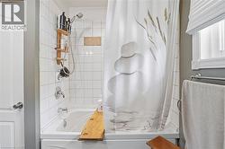 Bathtub and shower combination featuring white subway tile surround, chrome fixtures, and a window with horizontal blinds - 