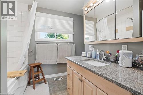 Bathroom featuring a single vanity with a granite-style countertop, undermount sink, and light wood-finish cabinetry - 25 Saveryn Road, Hamilton, ON - Indoor Photo Showing Bathroom