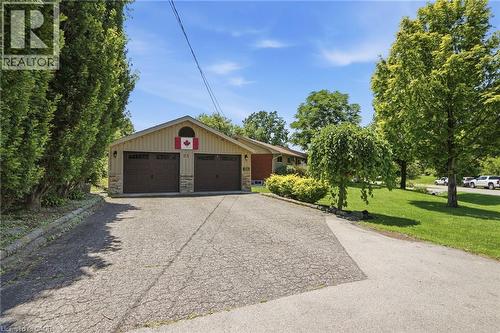 Double garage with two dark brown doors, stone detailing, and light-colored siding - 25 Saveryn Road, Hamilton, ON - Outdoor