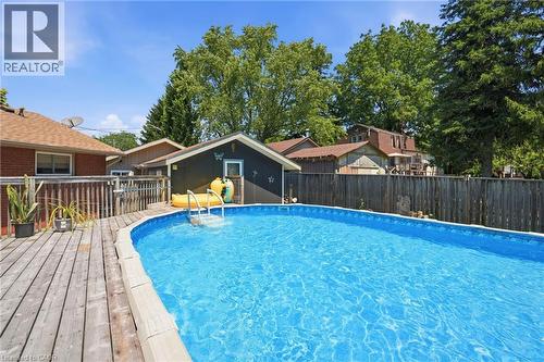 Expansive backyard featuring a large swimming pool with integrated steps, a surrounding wood deck, and a privacy fence - 25 Saveryn Road, Hamilton, ON - Outdoor With Above Ground Pool
