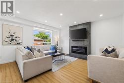 Living area featuring wood-finish flooring, recessed lighting, and a window with roller shades - 