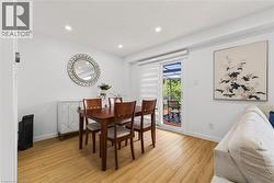 Light wood-finish flooring extending into a bright room with recessed lighting - 