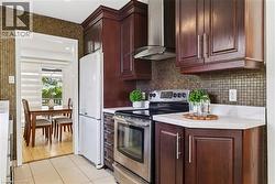 Kitchen featuring dark wood-finish cabinetry, stainless steel appliances, mosaic tile backsplash, and white countertops - 