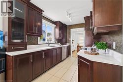 Galley kitchen featuring rich wood cabinetry, white countertops, a mosaic tile backsplash, and ceramic tile flooring - 