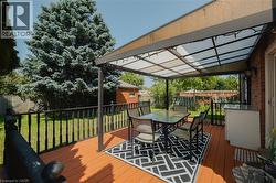 Expansive wooden deck featuring a covered pergola, outdoor cabinetry with a countertop, and black spindle railing - 