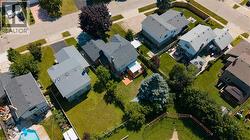 Aerial perspective of a neighborhood street featuring a residential property with a gabled roof and a spacious backyard - 