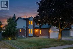 Two-story residence featuring a brick and siding exterior, bay window, front entry porch, attached garage, and mature landscaping - 