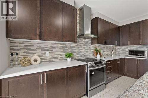 Kitchen featuring dark wood-finish cabinetry, light countertops, a mosaic tile backsplash, stainless steel appliances, and tile flooring - 96 Damselfly Way, Ottawa, ON - Indoor Photo Showing Kitchen With Upgraded Kitchen