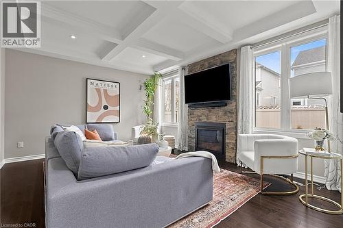 Living area featuring dark wood-finish flooring, a coffered ceiling with recessed lighting, and a stone-clad fireplace with a mounted television - 96 Damselfly Way, Ottawa, ON - Indoor Photo Showing Living Room With Fireplace